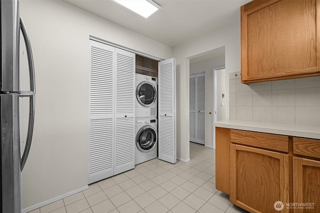 1964 26th Ave W Unit 102, Seattle, WA 98199 - laundry area with stacked washer / dryer, light tile patterned floors, and baseboards