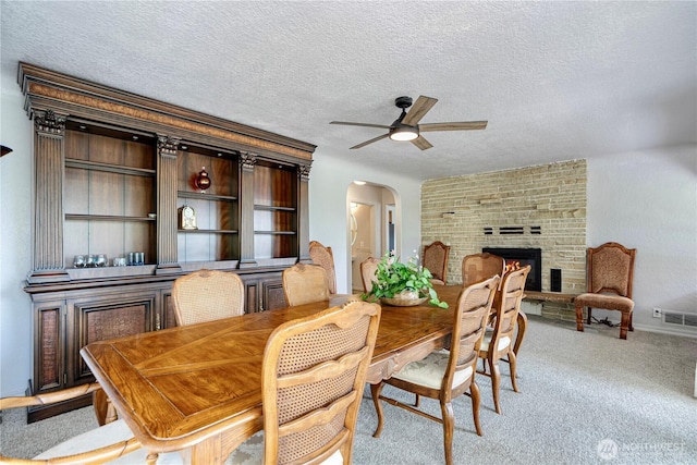 31111 53rd Ave SW, Federal Way, WA 98023 - dining space with arched walkways, ceiling fan, light colored carpet, a fireplace, and a textured ceiling