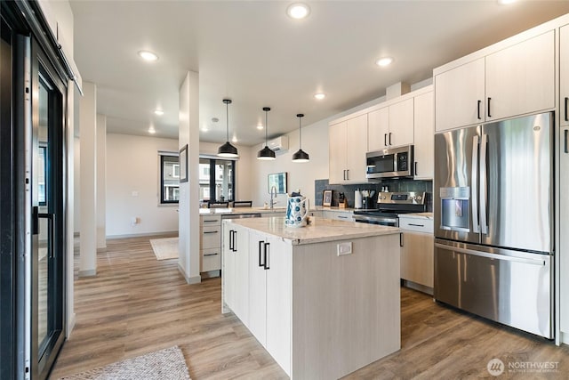4260 Creston Way, Bellingham, WA 98226 - kitchen with appliances with stainless steel finishes, a peninsula, a center island, hanging light fixtures, and light wood-style flooring