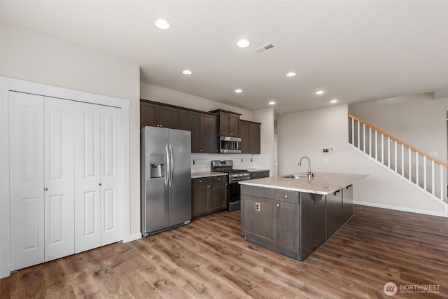 2719 Fiddleback St NE, Lacey, WA 98516 - kitchen featuring appliances with stainless steel finishes, a sink, dark brown cabinetry, wood finished floors, and backsplash