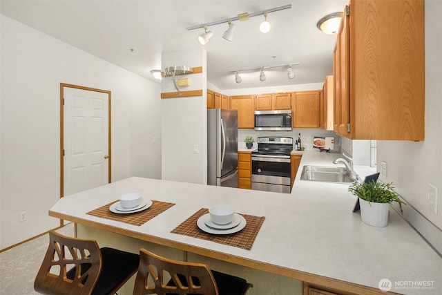 12315 NE 97th St Unit G, Kirkland, WA 98033 - kitchen with appliances with stainless steel finishes, light countertops, a peninsula, a breakfast bar area, and brown cabinets