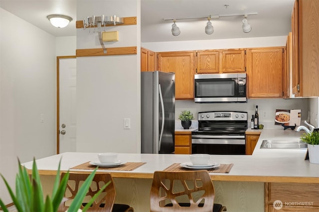 12315 NE 97th St Unit G, Kirkland, WA 98033 - kitchen featuring appliances with stainless steel finishes, light countertops, a peninsula, and a breakfast bar
