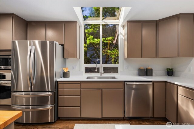 16939 SE 39th St, Bellevue, WA 98008 - kitchen featuring appliances with stainless steel finishes, a sink, a skylight, light countertops, and dark wood finished floors