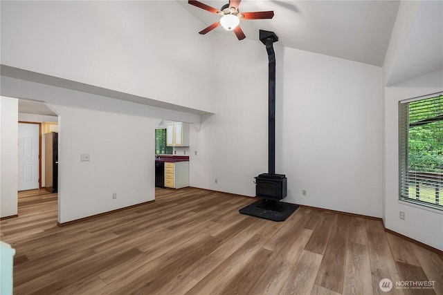 7549 Siskin Dr SE, Olympia, WA 98513 - unfurnished living room with a wood stove, high vaulted ceiling, ceiling fan, light wood-style flooring, and baseboards
