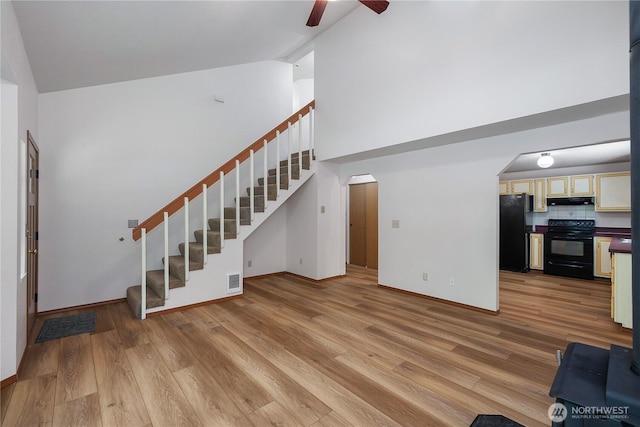 7549 Siskin Dr SE, Olympia, WA 98513 - unfurnished living room with stairway, arched walkways, high vaulted ceiling, ceiling fan, and light wood-style flooring