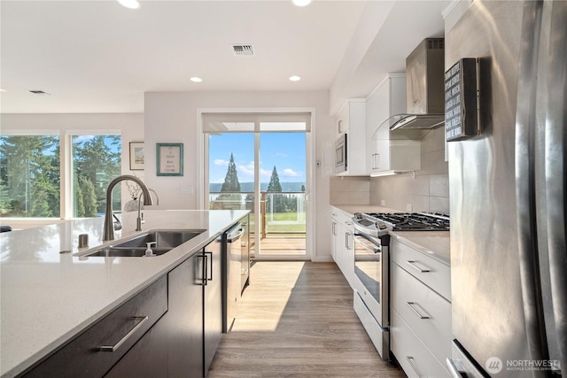 70 Ida Ct, Sequim, WA 98382 - kitchen with stainless steel appliances, a sink, wall chimney range hood, light countertops, and recessed lighting