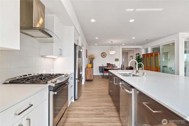 70 Ida Ct, Sequim, WA 98382 - kitchen with appliances with stainless steel finishes, a sink, wall chimney range hood, light wood-style floors, and light countertops