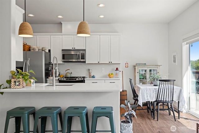 5695 Meadow View Dr, Ferndale, WA 98248 - kitchen with appliances with stainless steel finishes, a peninsula, light countertops, tasteful backsplash, and white cabinetry