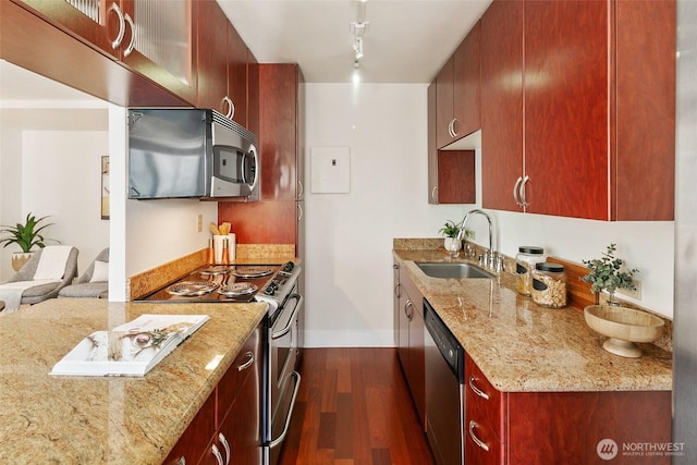 1105 Spring St Unit 712, Seattle, WA 98104 - kitchen with appliances with stainless steel finishes, dark wood-style floors, light stone counters, reddish brown cabinets, and track lighting