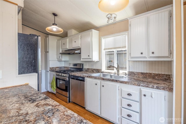 7515 Sunset Dr, Blaine, WA 98230 - kitchen featuring under cabinet range hood, stainless steel appliances, a sink, and dark countertops