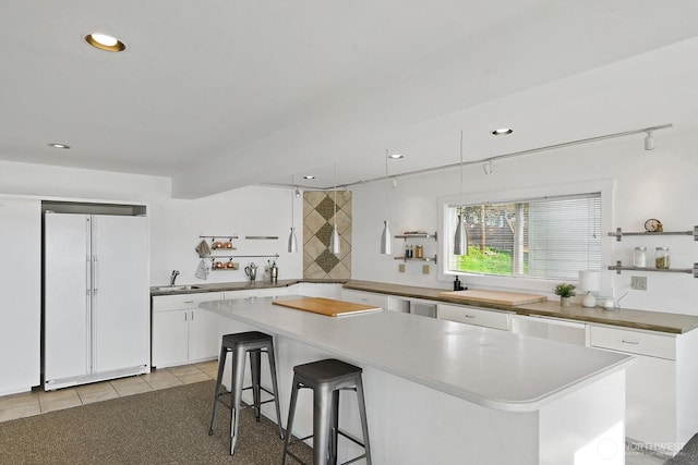 11613 SW Shawnee, Vashon, WA 98070 - kitchen with built in fridge, a sink, white cabinetry, a kitchen island, and a breakfast bar area