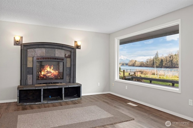 8789 Cedar Ct, Sedro Woolley, WA 98284 - unfurnished living room featuring wood finished floors, a fireplace, a textured ceiling, and baseboards