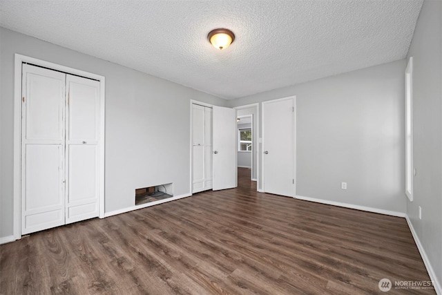 8789 Cedar Ct, Sedro Woolley, WA 98284 - unfurnished bedroom featuring multiple closets, wood finished floors, a textured ceiling, and baseboards