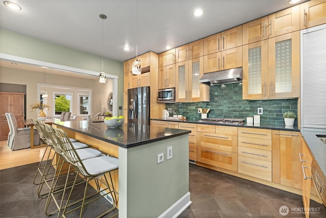 1218 NE 69th St, Seattle, WA 98115 - kitchen featuring stainless steel appliances, under cabinet range hood, light brown cabinets, a breakfast bar, and backsplash