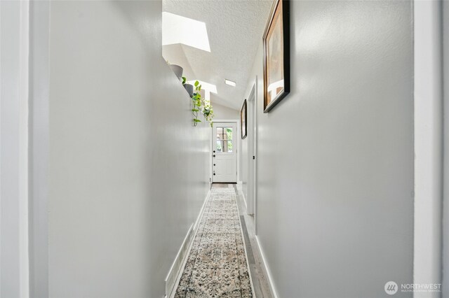 513 SE Highland Park Dr, College Place, WA 99324 - corridor with lofted ceiling, a skylight, a textured ceiling, and baseboards