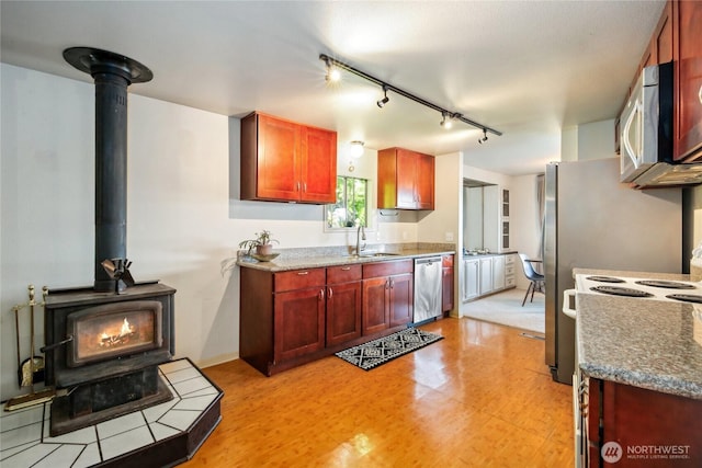 70 E Rustle Way, Grapeview, WA 98546 - kitchen featuring appliances with stainless steel finishes, a wood stove, dark brown cabinets, track lighting, and a sink