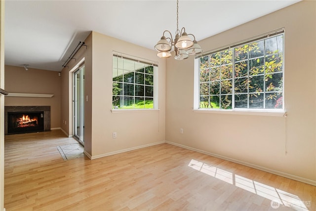 7453 Newcastle Golf Club Rd Unit B103, Newcastle, WA 98059 - unfurnished dining area featuring wood finished floors, a chandelier, a warm lit fireplace, and baseboards