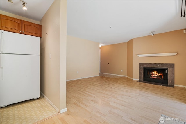 7453 Newcastle Golf Club Rd Unit B103, Newcastle, WA 98059 - kitchen featuring freestanding refrigerator, light wood-style floors, a high end fireplace, brown cabinets, and baseboards