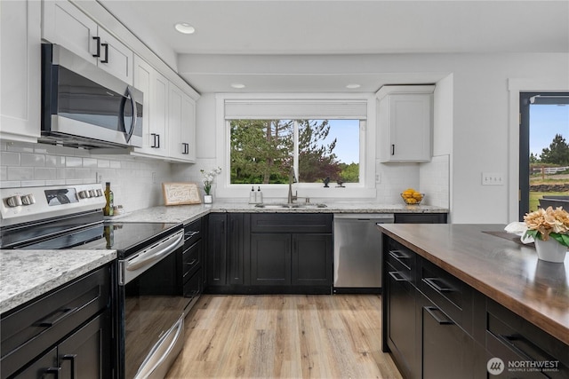 9906 328th St E, Graham, WA 98338 - kitchen with appliances with stainless steel finishes, a sink, healthy amount of natural light, white cabinets, and recessed lighting