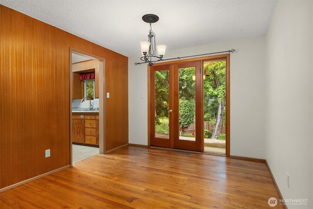10210 NE 23rd St, Bellevue, WA 98004 - entrance foyer with a chandelier, light wood-style floors, wood walls, baseboards, and a textured ceiling