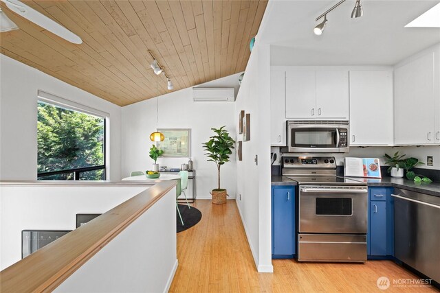 4618 3rd Ave NW, Seattle, WA 98107 - kitchen featuring stainless steel appliances, track lighting, blue cabinetry, vaulted ceiling, and an AC wall unit