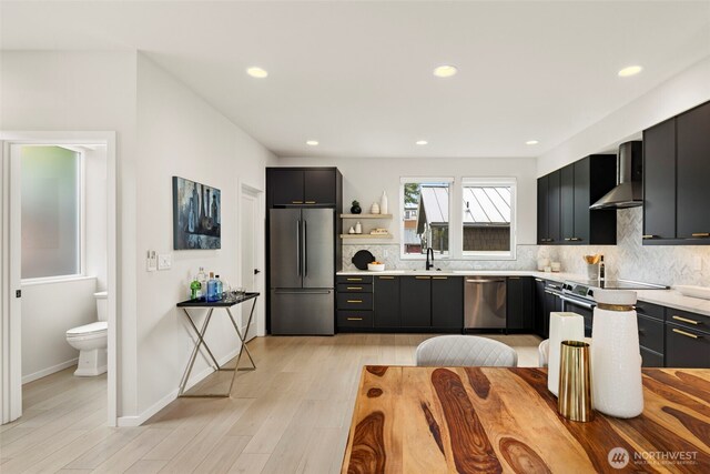 2014 E Pine St Unit A, Seattle, WA 98122 - kitchen with appliances with stainless steel finishes, wall chimney exhaust hood, dark cabinets, backsplash, and recessed lighting