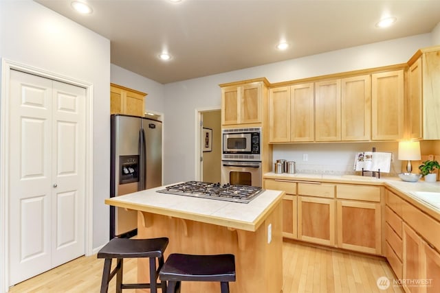 1913 NE 32nd St, Renton, WA 98056 - kitchen featuring appliances with stainless steel finishes, light brown cabinets, light wood-type flooring, a breakfast bar area, and recessed lighting