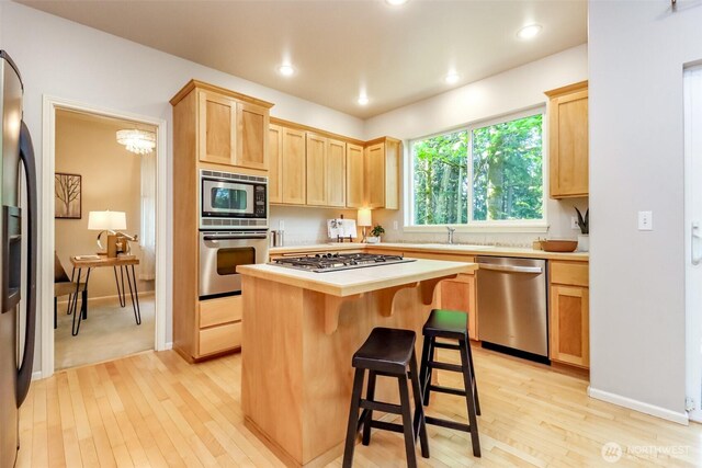 1913 NE 32nd St, Renton, WA 98056 - kitchen featuring stainless steel appliances, light brown cabinets, light countertops, light wood finished floors, and a kitchen island