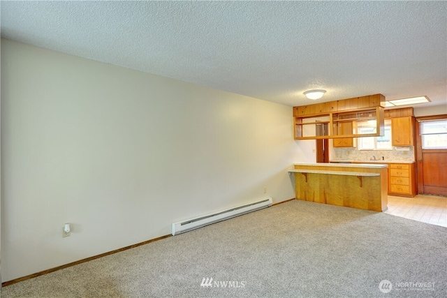 16327 Smokey Point Blvd Unit 1 & 2, Marysville, WA 98271 - kitchen featuring baseboard heating, a peninsula, light colored carpet, a textured ceiling, and brown cabinetry