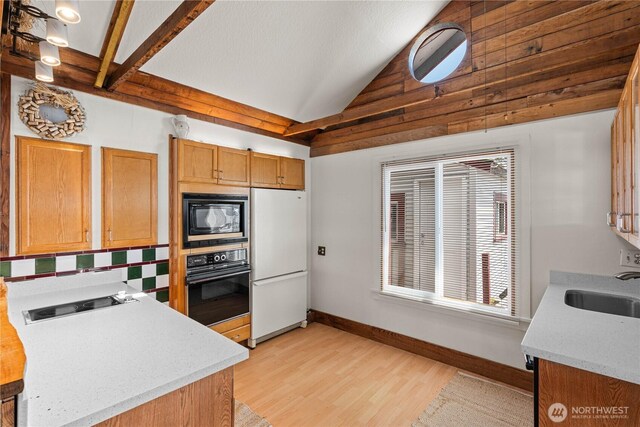 24186 Vashon Hwy SW, Vashon, WA 98070 - kitchen with black appliances, lofted ceiling, light wood finished floors, a sink, and baseboards