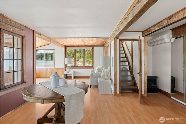 24186 Vashon Hwy SW, Vashon, WA 98070 - dining space featuring an AC wall unit, light wood-style floors, stairs, a wood stove, and vaulted ceiling