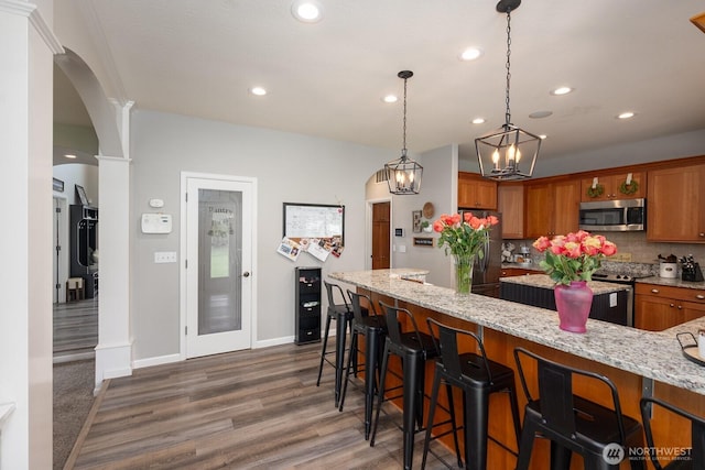 331 Viewmont Dr SE, Moses Lake, WA 98837 - kitchen with stainless steel appliances, brown cabinetry, arched walkways, backsplash, and wood finished floors
