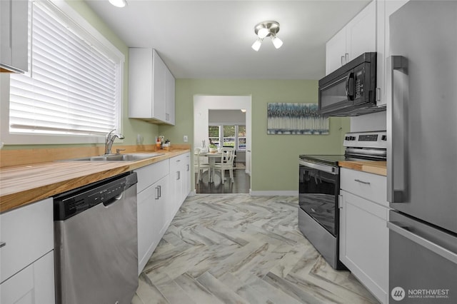 2409 Lombard Ave Unit C, Everett, WA 98201 - kitchen with appliances with stainless steel finishes, a sink, butcher block countertops, white cabinets, and baseboards