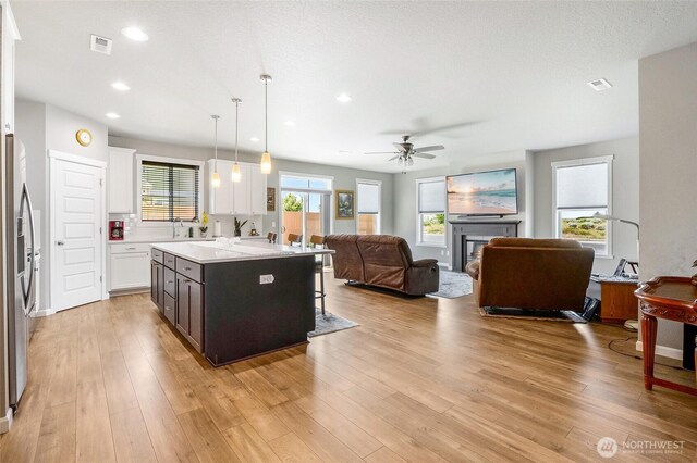 4737 W Owl St, Moses Lake, WA 98837 - kitchen with open floor plan, a ceiling fan, white cabinetry, a breakfast bar, and a kitchen island with sink