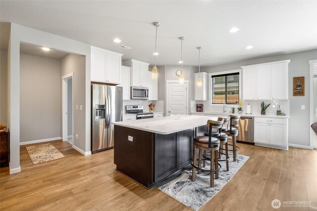 4737 W Owl St, Moses Lake, WA 98837 - kitchen with stainless steel appliances, light countertops, a center island, white cabinetry, and light wood-style floors