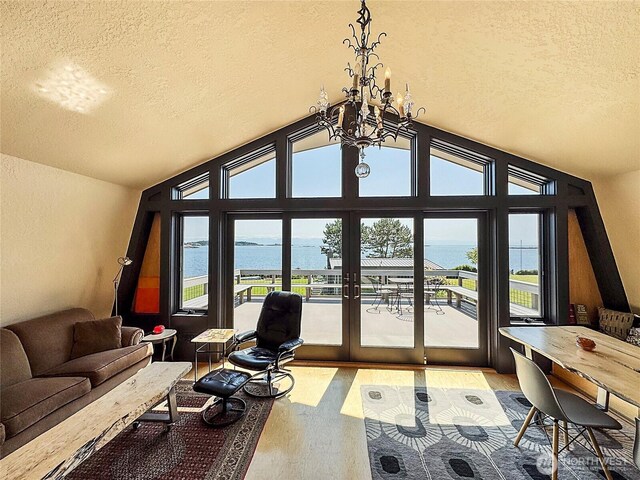 62 Wildwood Ln, Lopez Island, WA 98261 - living room with a textured ceiling, a water view, light wood finished floors, a chandelier, and vaulted ceiling