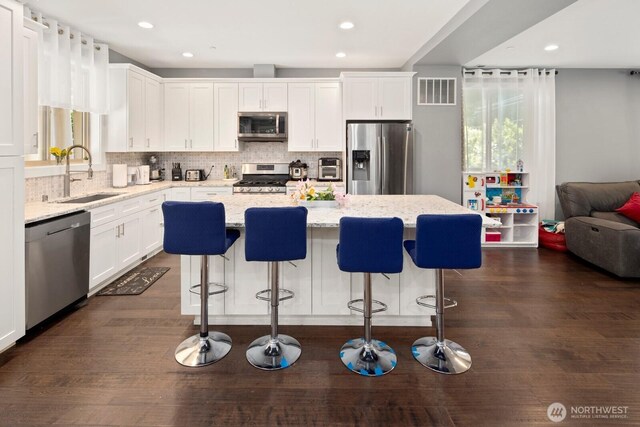 16422 76th Ave NE, Kenmore, WA 98028 - kitchen with a sink, appliances with stainless steel finishes, white cabinets, decorative backsplash, and a kitchen island