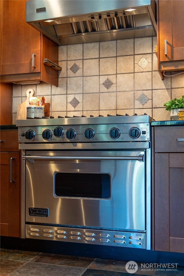 2942 222nd Pl SE, Sammamish, WA 98075 - kitchen featuring exhaust hood, dark countertops, tasteful backsplash, brown cabinets, and luxury stove