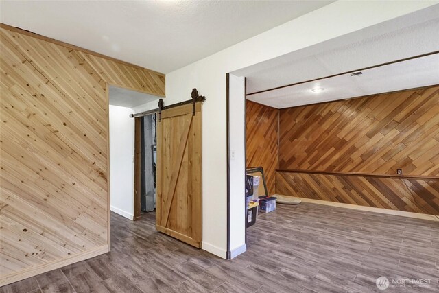 3125 Mcleod Rd, Bellingham, WA 98225 - empty room featuring wood walls, baseboards, wood finished floors, and a barn door