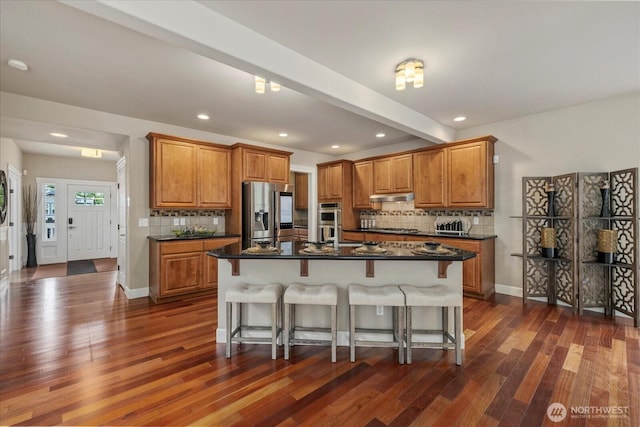 7320 111th Pl SE, Newcastle, WA 98056 - kitchen featuring appliances with stainless steel finishes, brown cabinets, under cabinet range hood, tasteful backsplash, and recessed lighting