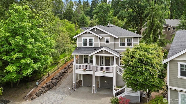 7320 111th Pl SE, Newcastle, WA 98056 - view of front of home featuring a shingled roof, concrete driveway, a garage, covered porch, and stairway