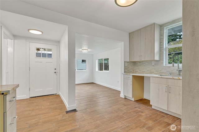 4117 S M St, Tacoma, WA 98418 - kitchen with a sink, light countertops, light wood-style flooring, decorative backsplash, and light brown cabinets