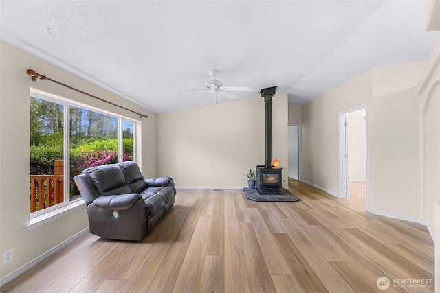 2957 Unick Rd, Ferndale, WA 98248 - living room featuring light wood-style floors, a wood stove, a ceiling fan, baseboards, and lofted ceiling