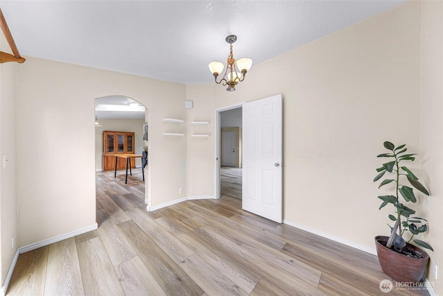 2957 Unick Rd, Ferndale, WA 98248 - empty room featuring arched walkways, a chandelier, light wood-style flooring, and baseboards