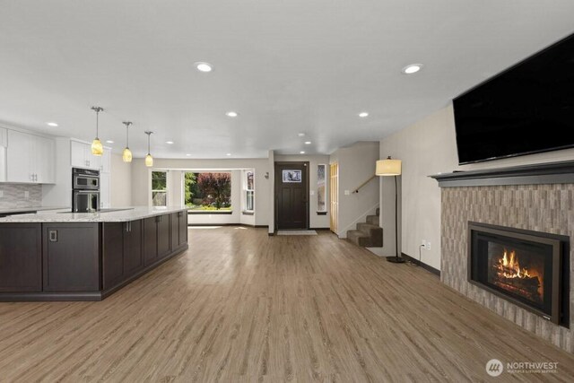 5208 S 380th St, Auburn, WA 98001 - kitchen with white cabinetry, a glass covered fireplace, light wood-type flooring, recessed lighting, and dark brown cabinets