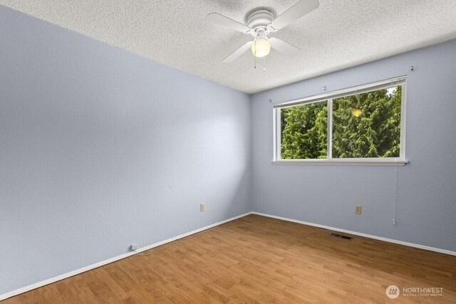 5208 S 380th St, Auburn, WA 98001 - spare room with a textured ceiling, wood finished floors, and a ceiling fan