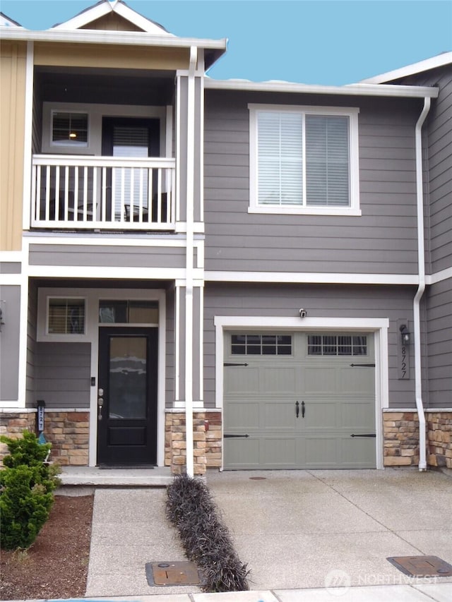8727 E Gilman Ave, Arlington, WA 98223 - view of front of home with a balcony, stone siding, an attached garage, and concrete driveway