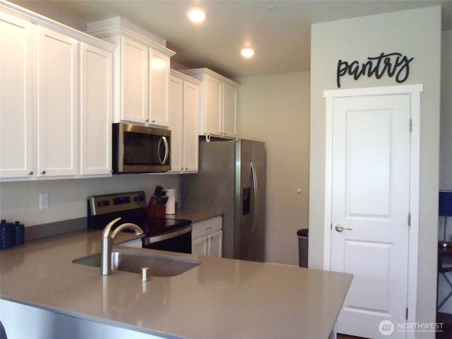 8727 E Gilman Ave, Arlington, WA 98223 - kitchen featuring appliances with stainless steel finishes, a sink, white cabinets, recessed lighting, and a peninsula