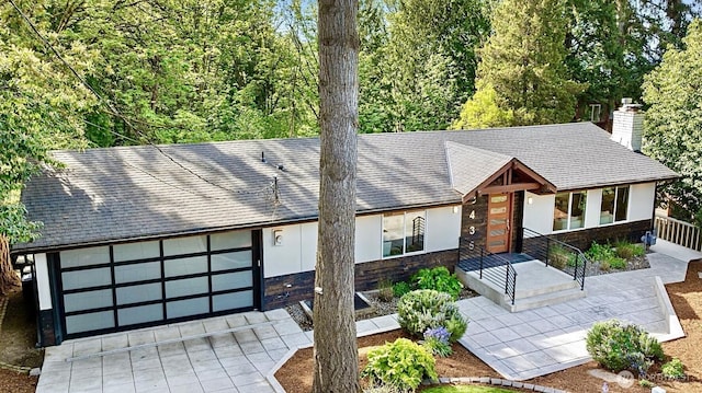 3435 103rd Pl NE, Bellevue, WA 98004 - view of front of property featuring a chimney, stone siding, driveway, roof with shingles, and stucco siding