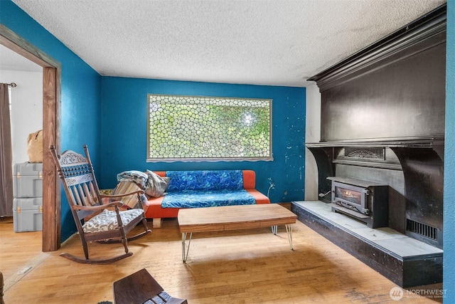 9139 Burnett Rd SE, Yelm, WA 98597 - sitting room with a wood stove, a textured ceiling, and wood finished floors